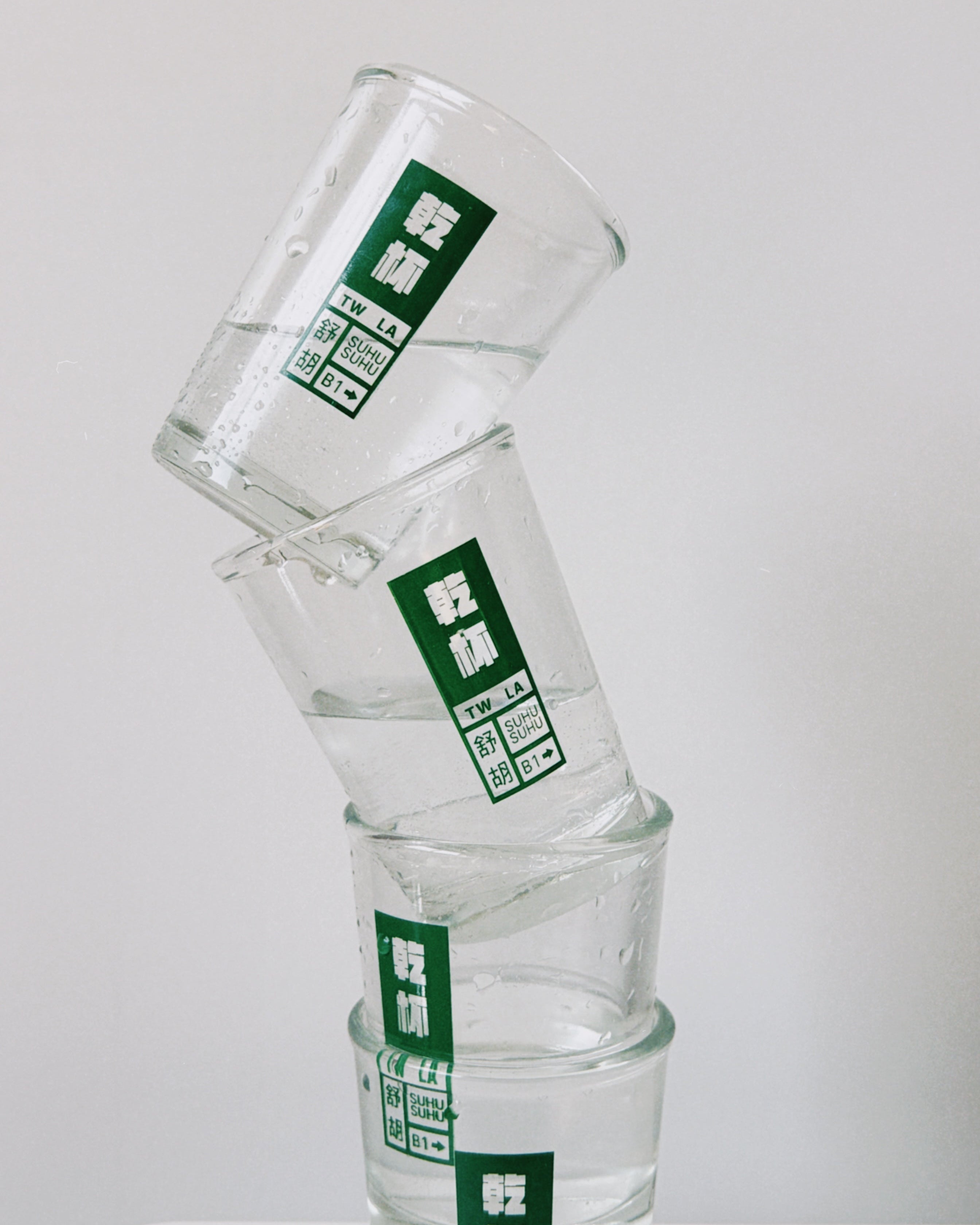 Stack of clear glasses with green labels on a white background