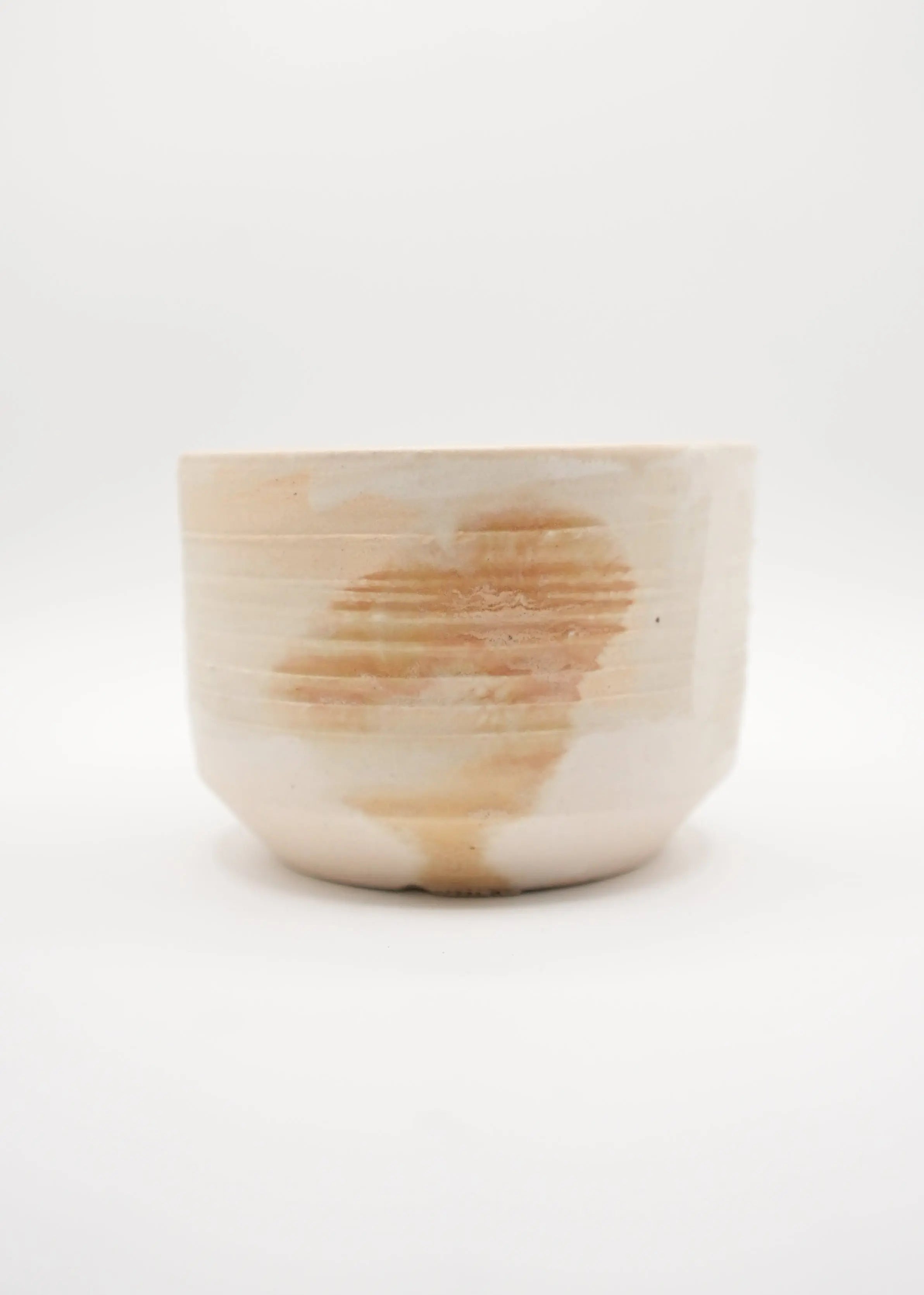 A handmade ceramic bowl with a textured, ribbed exterior and a warm, earthy brown and beige marbled pattern, photographed against a seamless white background.