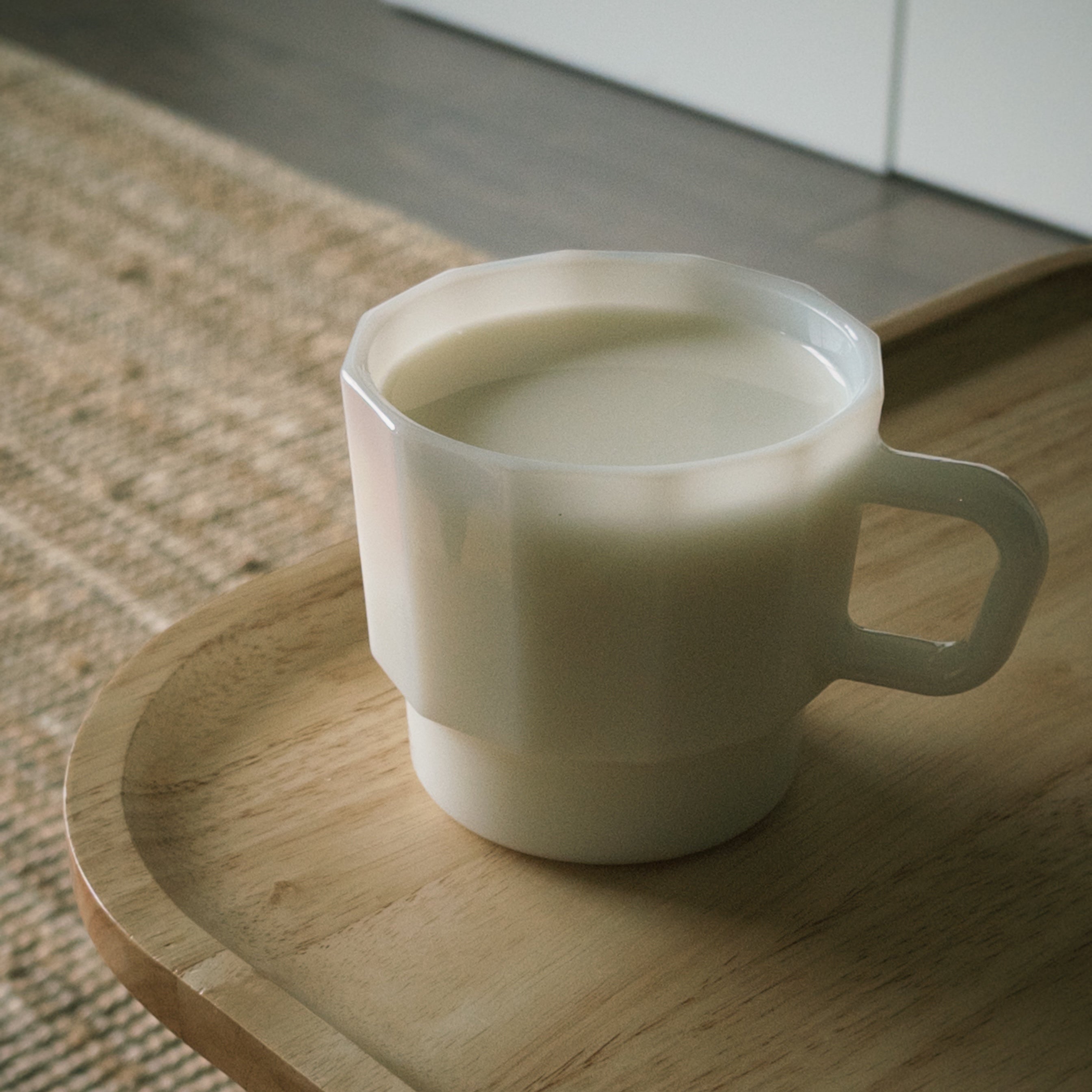 White mug with milk on a wooden tray