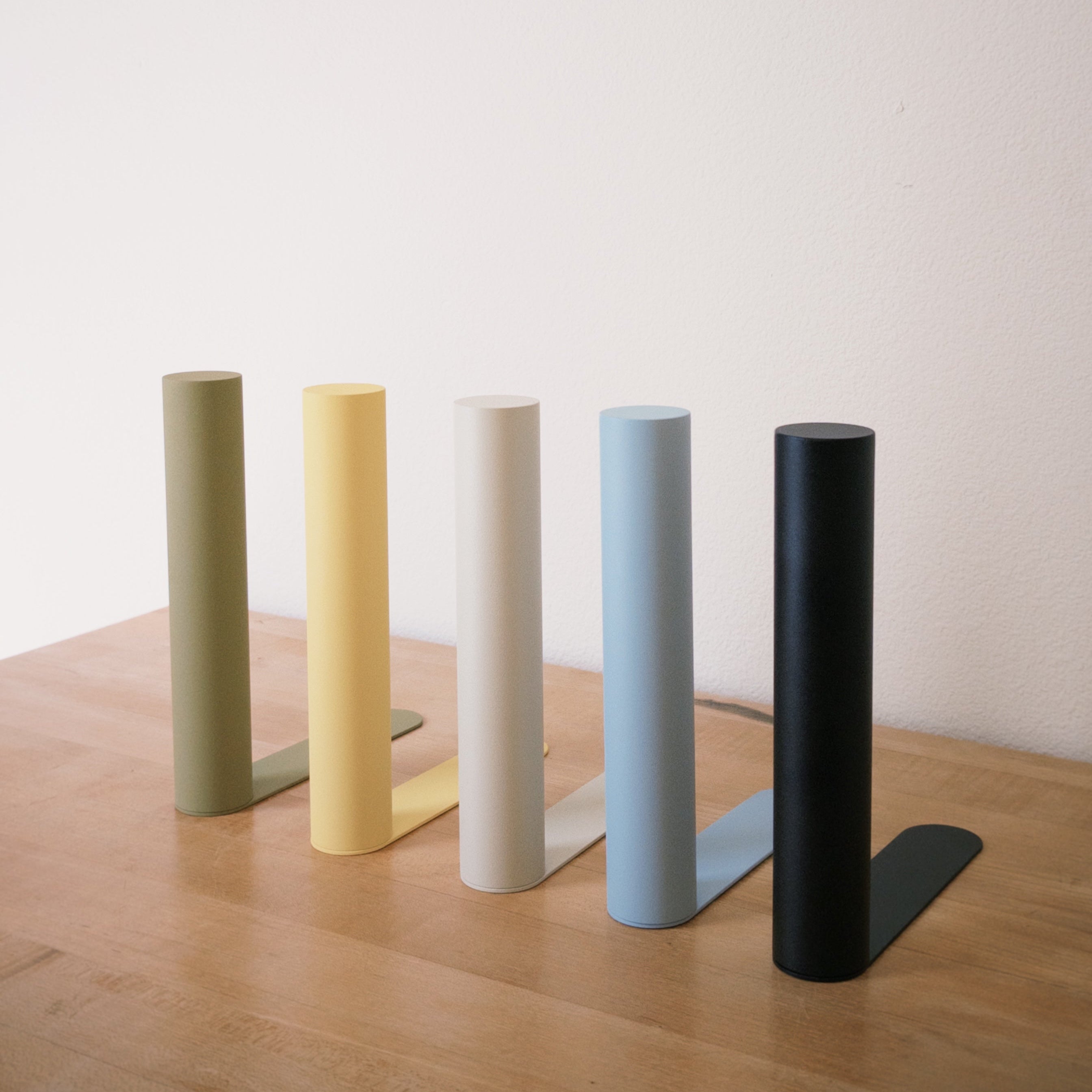 Five bookends in different colors on a wooden surface with a plain background