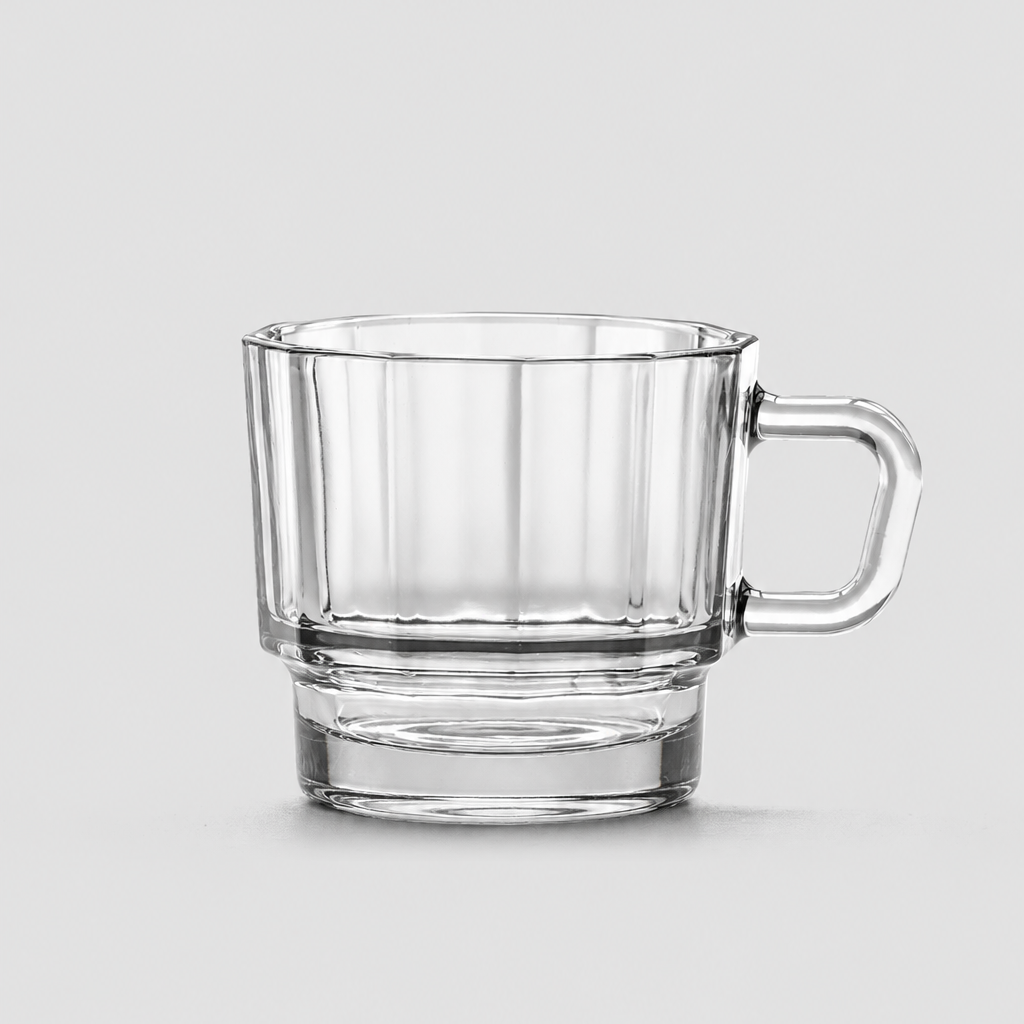 A clear glass mug with a handle, featuring a ribbed exterior and a thick base, shown on a neutral light gray background.