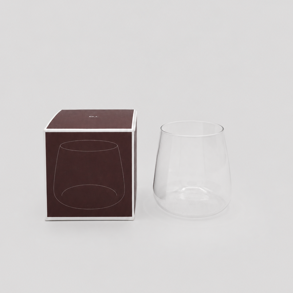 Clear white wine glass with its packaging on a light gray background